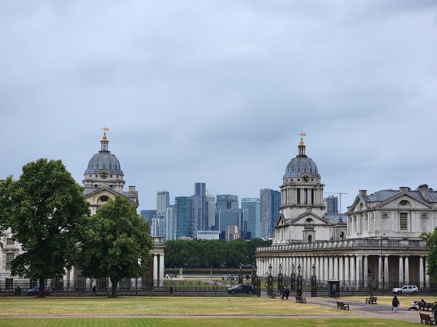A wide-angle daytime view of historical church buildings with classical architectural features, including domed roofs topped with gold crosses, set against a backdrop of modern high-rise office buildings with glass facades in a city skyline. The foreground features a well-maintained grassy area with several mature trees, some with lush green foliage, and paved pathways where a few pedestrians are walking. The sky is overcast with grey clouds, creating a muted lighting environment. The scene appears to be in an urban park or open space adjacent to the city center, with the church structures suggesting heritage or landmark status. The image subtly relates to alternative waste handling concepts by highlighting preservation amidst urban development, with the apparent presence of waste collection or clearance services possibly operating nearby or in the context of maintaining such historic sites. The overall setting exhibits a mixture of historic architecture and modern cityscape, reflecting the area's development status and potential for independent rubbish removal or site clearance, consistent with services offered in the vicinity. House Clearance Canary Wharf might facilitate waste disposal for such areas, ensuring suitable rubbish management in sustainable environments.