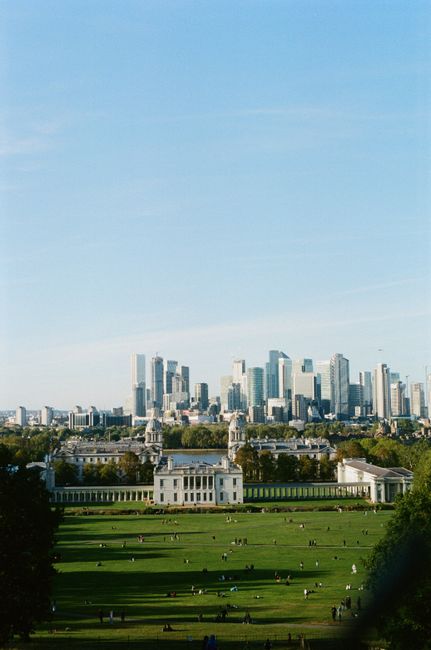 A wide-angle daytime view of historical church buildings with classical architectural features, including domed roofs topped with gold crosses, set against a backdrop of modern high-rise office buildings with glass facades in a city skyline. The foreground features a well-maintained grassy area with several mature trees, some with lush green foliage, and paved pathways where a few pedestrians are walking. The sky is overcast with grey clouds, creating a muted lighting environment. The scene appears to be in an urban park or open space adjacent to the city center, with the church structures suggesting heritage or landmark status. The image subtly relates to alternative waste handling concepts by highlighting preservation amidst urban development, with the apparent presence of waste collection or clearance services possibly operating nearby or in the context of maintaining such historic sites. The overall setting exhibits a mixture of historic architecture and modern cityscape, reflecting the area's development status and potential for independent rubbish removal or site clearance, consistent with services offered in the vicinity. House Clearance Canary Wharf might facilitate waste disposal for such areas, ensuring suitable rubbish management in sustainable environments.